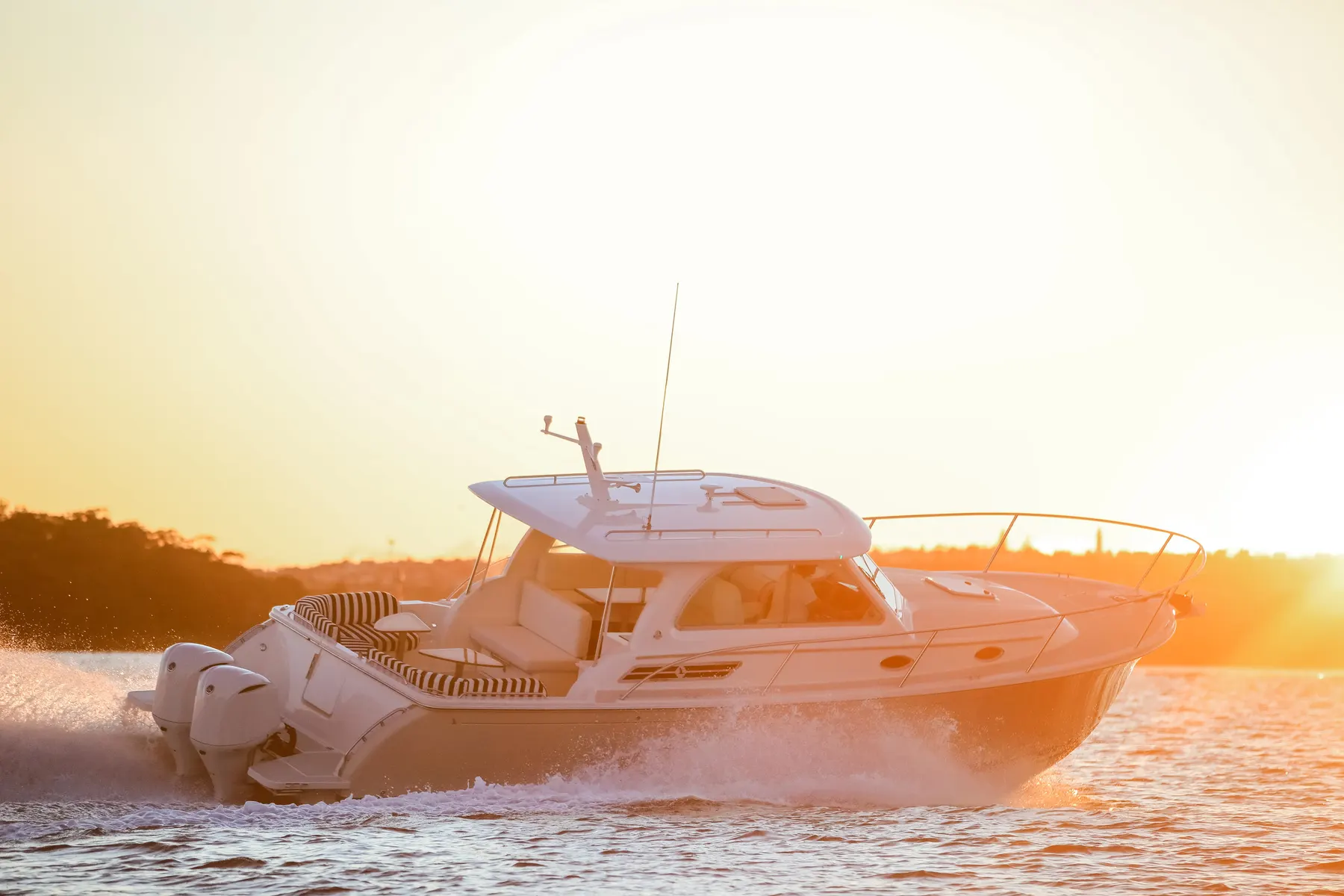 A motor boat silhouetted against a golden sunset on the water
