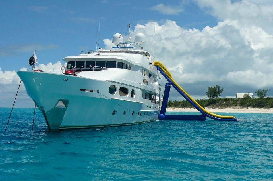 A large white superyacht at anchor off a Caribbean beach