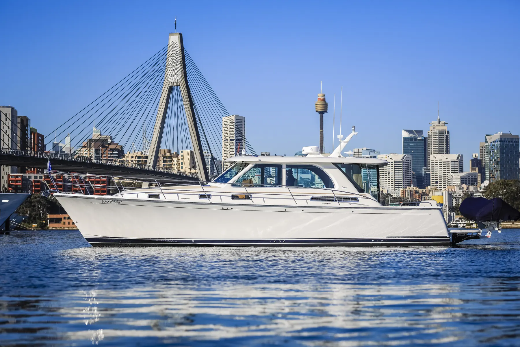A motor yacht on Sydney Harbour with the Anzac Bridge and city skyline behind