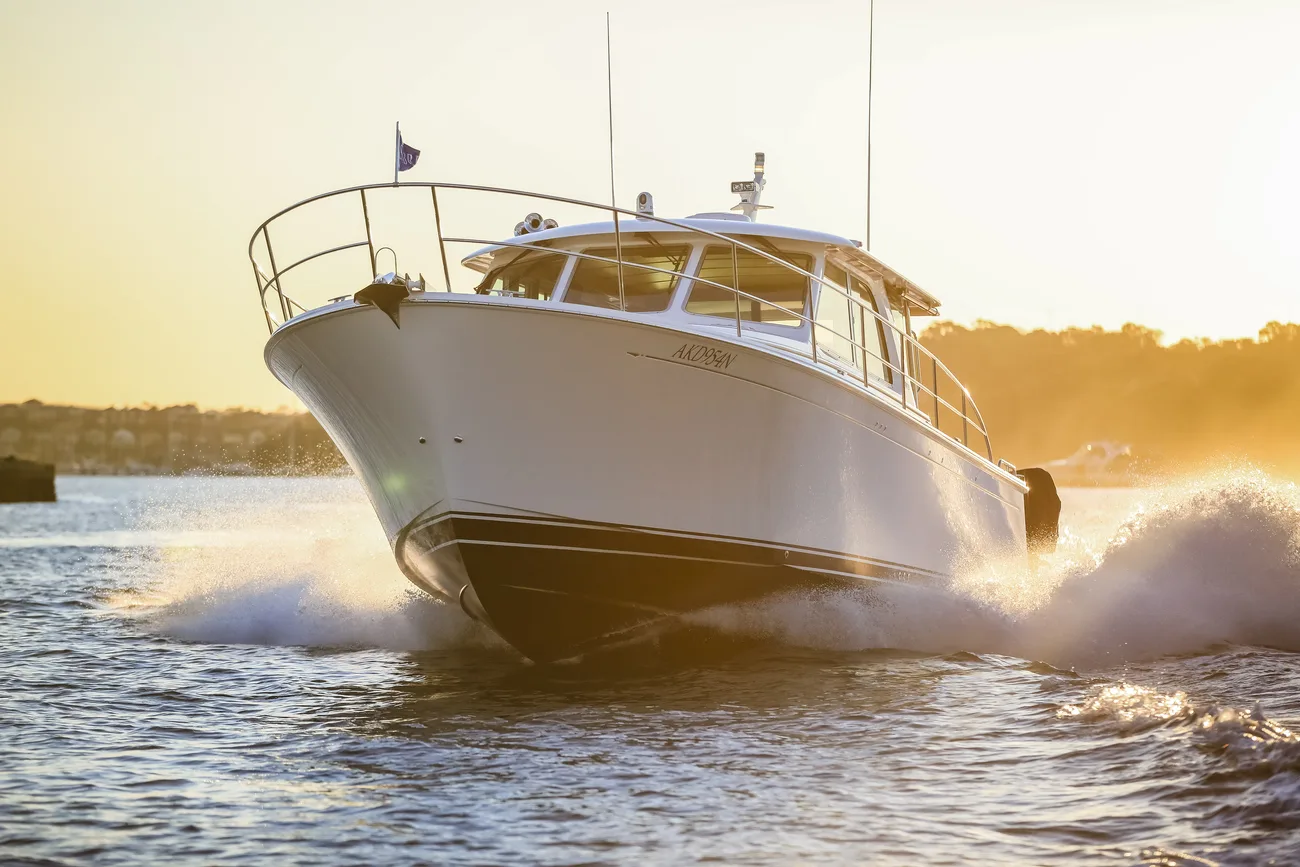 A white motor yacht bow-on at speed in golden evening light
